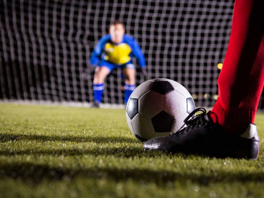 Voetbalspeler die op het punt staat een bal op doel te schieten.