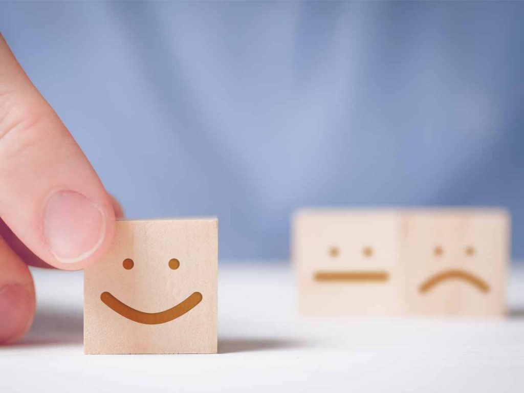 Een houten blokje met een blije smiley.