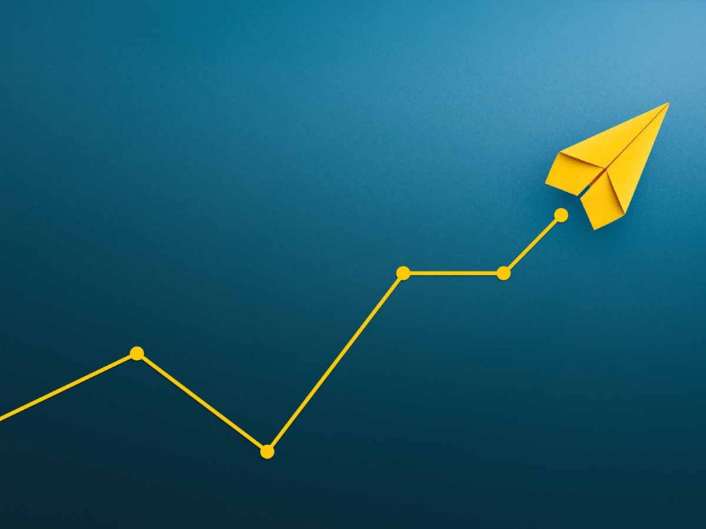Blauwe achtergrond met een geel papieren vliegtuigje dat een lijngrafiek omhoog maakt.