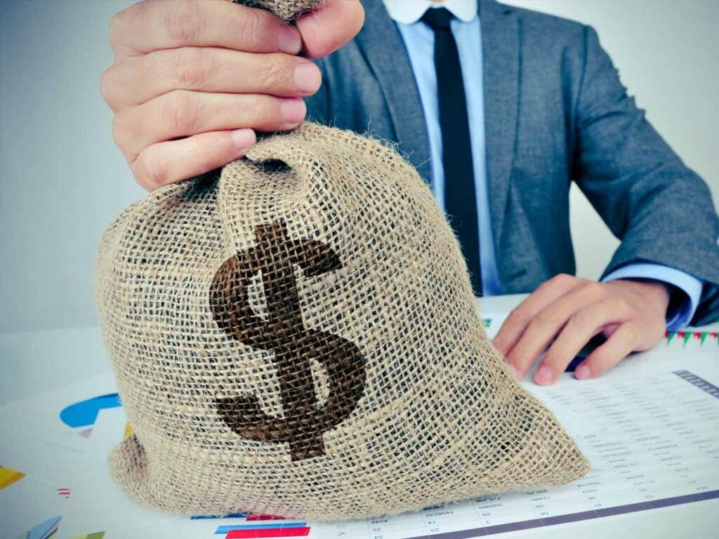 Zakenman die een juten zak met een dollarteken vast heeft.